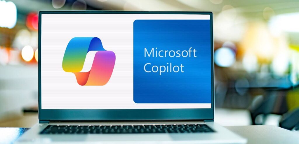 Un ordinateur portable ouvert dans les locaux d'un bureau qui affiche le logo de microsoft copilot